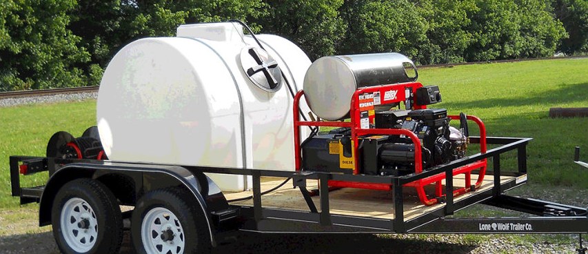 Enzo's custom built pressure washer trailer with a large water tank and hot water diesel burner, parked in a field for on-site cleaning of farm equipment